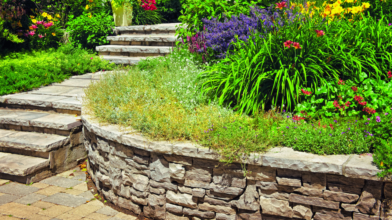 Beautifully landscaped garden with a stone retaining wall, steps, and vibrant flowers adding aesthetic value and functionality to the outdoor space.